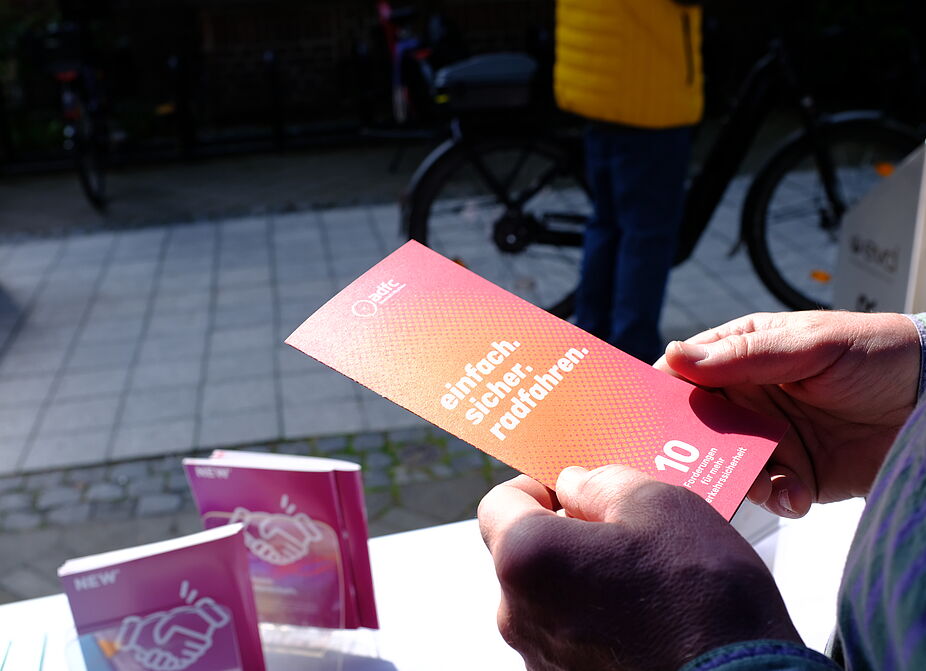 2026-04-17_Dormagen_Verkehrssicherheit__ADFC_NRW Eine Person hält einen Flyer.