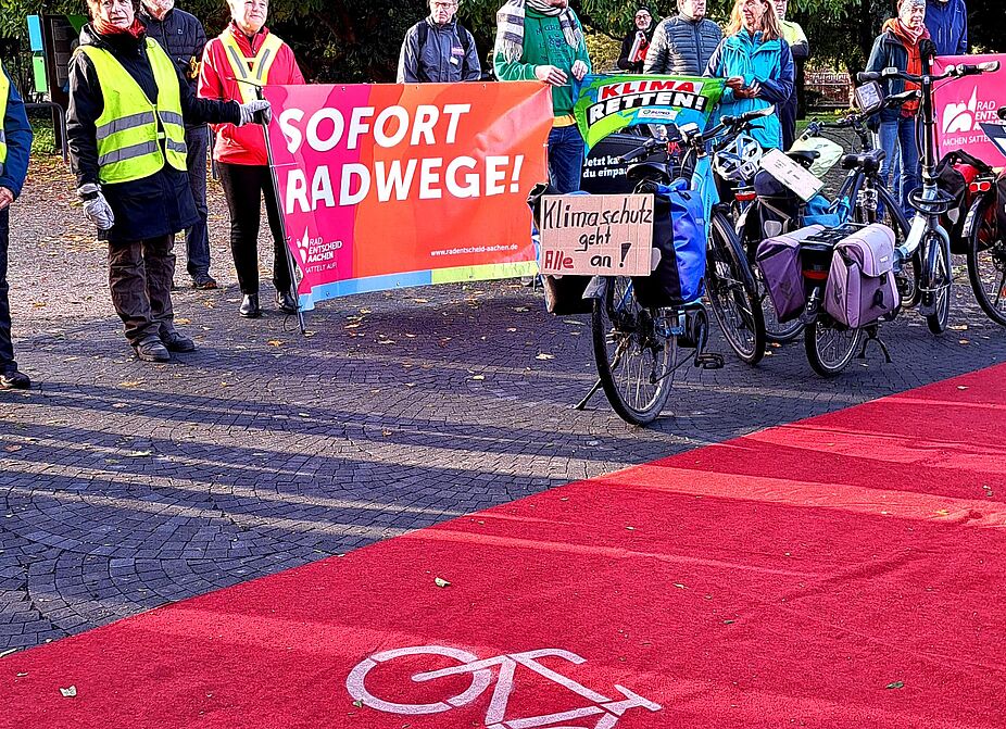 Auftaktveranstaltung in Aachen zur COP31 Radtour RRadfahrerinnen und Radfahrer fordern auf einem Plakat Sofort Radwege bei der Auftaktveranstaltung in Aachen.