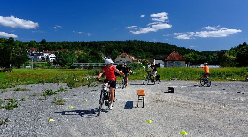 In einer kleinen Gruppe üben Teilnehmerinnen und Teilnehmer , richtig mit ihrem E-Bike ab- und aufzusteigen