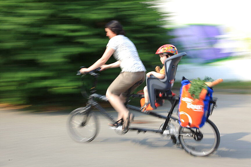 Mit dem ADFC immer aktuell unterwegs Eine Frau fährt mit Kind und ihren Einkauf auf einem Elektrofahrrad