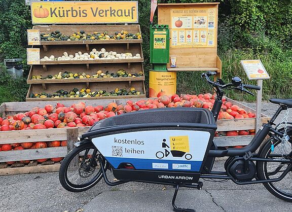 Das Ulf-Lastenrad des ADFC mit seinem Logo. Es ist vor einem Kürbisstand geparkt.