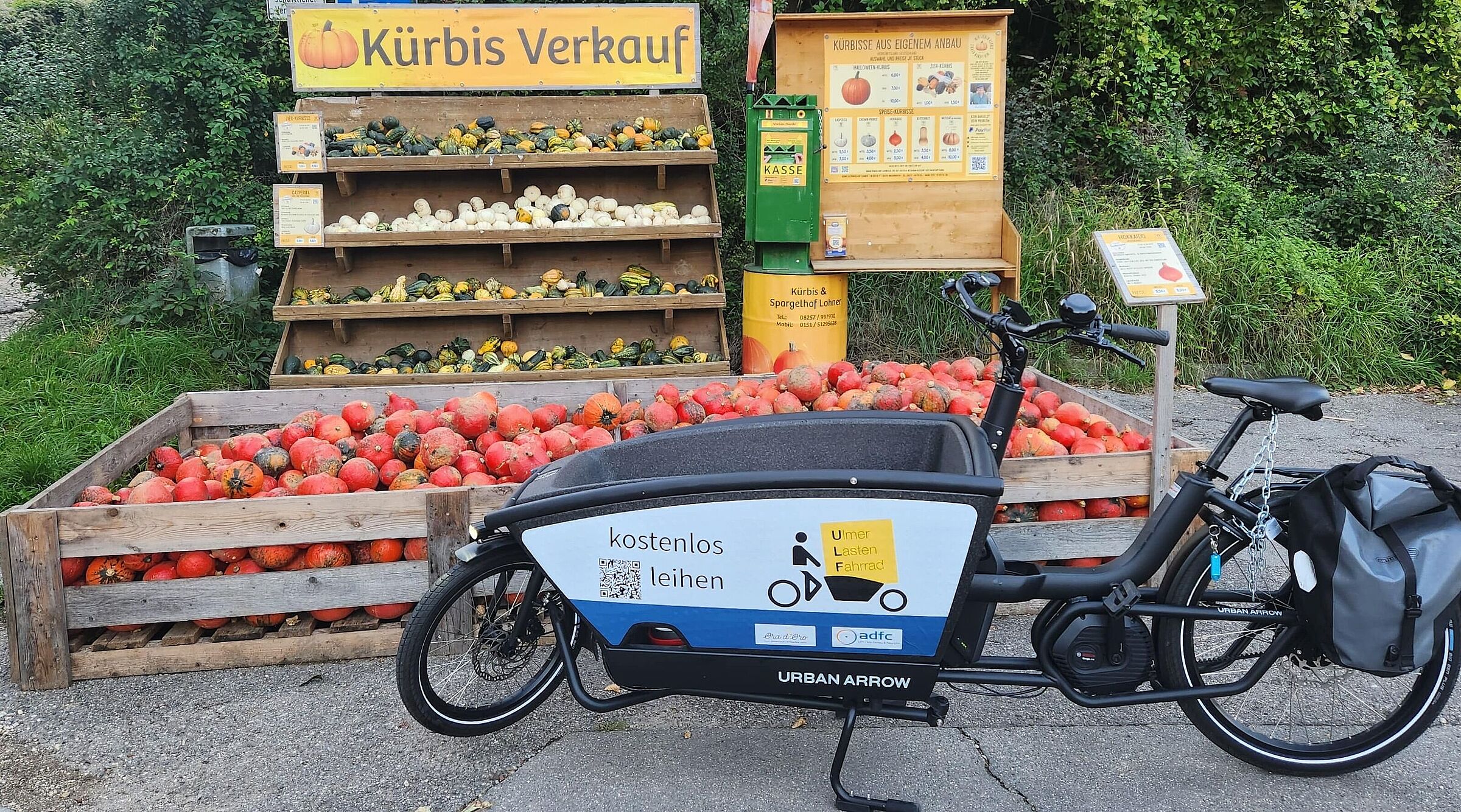 Das Ulf-Lastenrad des ADFC mit seinem Logo. Es ist vor einem Kürbisstand geparkt.